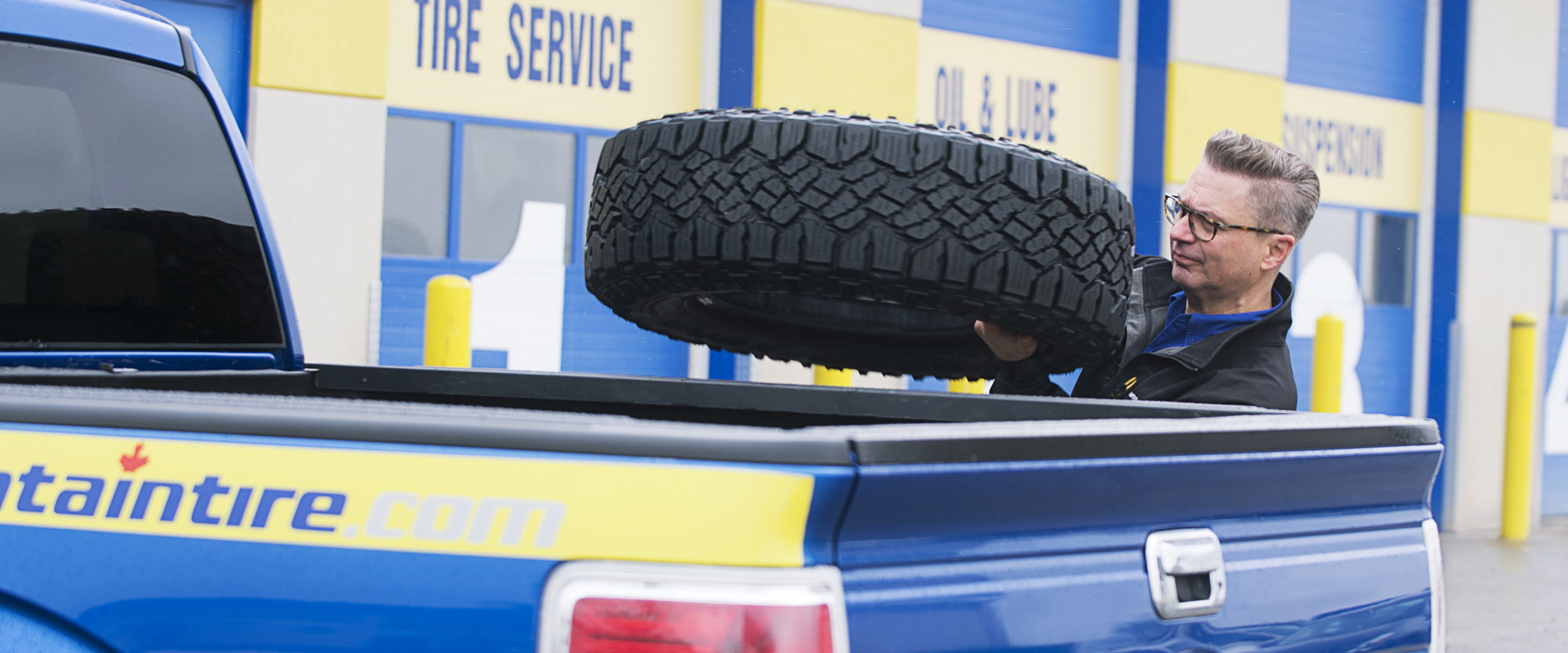 Man putting tire into a pickup truck